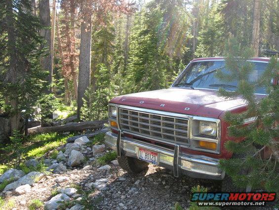 Red Ford pickup truck parked on a rocky, wooded trail. License plate reads IL 80120