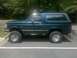 1994 Ford Bronco - Side profile of a teal Ford Bronco with a dark removable top and large off-road tires.
