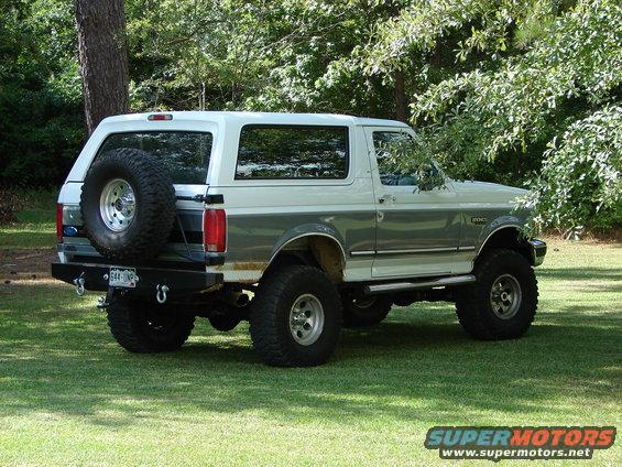 Lifted 1995 Ford Bronco parked on grass, rear-mounted spare tire visible