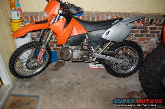 Orange dirt bike with black seat and silver side panels, parked indoors