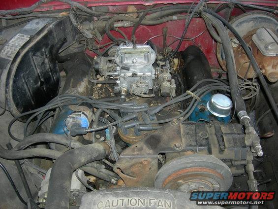 Engine bay of a 1979 Ford Bronco with a V8 engine, carburetor, and distributor. Red paint visible
