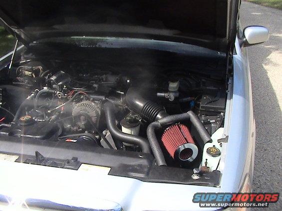 2000 Ford Crown Victoria engine bay showing V8 engine, aftermarket red cone air filter, and intake piping