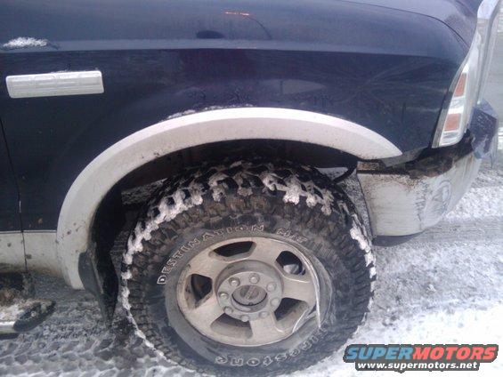 Dark blue 2005 Ford F-250 front fender and wheel with snow on tire