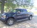 2005 Ford F-250 - This dark blue 2005 Ford F-250 crew cab pickup truck is seen from a three-quarter front angle, parked outdoors under a tree.