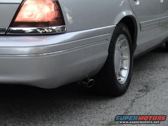 Silver 2000 Ford Crown Victoria rear side, showing taillight, chrome trim, exhaust pipe, and wheel