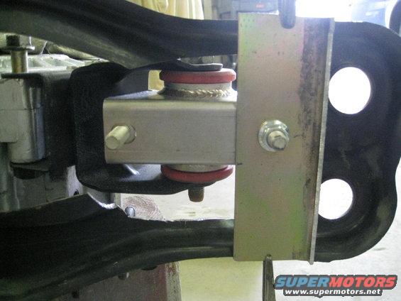 Close-up of a suspension part with red bushings and metal brackets