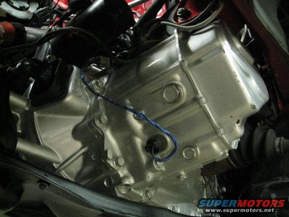 Close-up of a car's engine and transmission assembly, showing metal casing and wiring