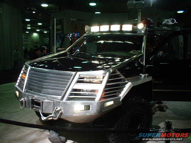 Front view of a black SUV with a large silver grille, bull bar, and multiple lights on the roof