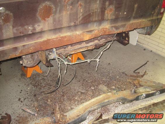 rusted vehicle frame and undercarriage supported by orange jack stands