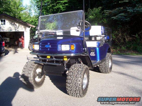 Blue golf cart with off-road tires and a Ford emblem on the grille