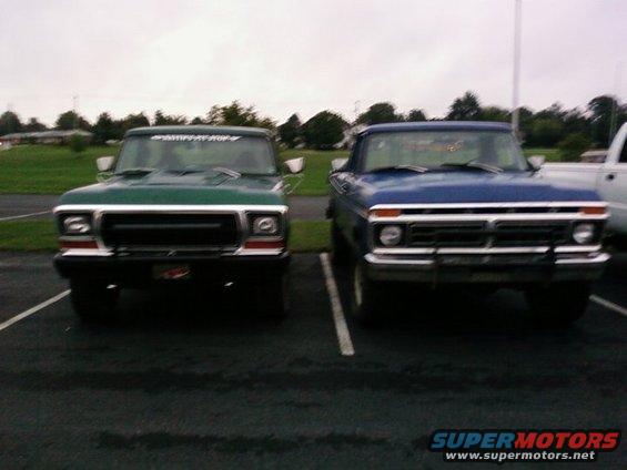 Green and blue pickup trucks parked front-end out in a lot. The green truck is on the left