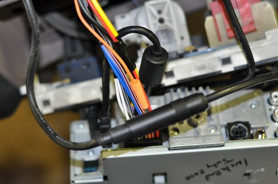 Car stereo wiring harness with multiple colored wires and connectors. Text on stereo reads 'Luke Hill July 2010'