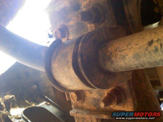 Close-up of heavily rusted suspension components with bolts and a pipe