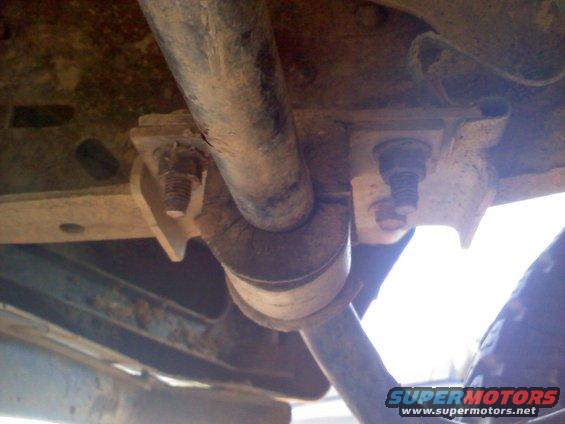 Close-up of rusty suspension parts with bolts and a pipe
