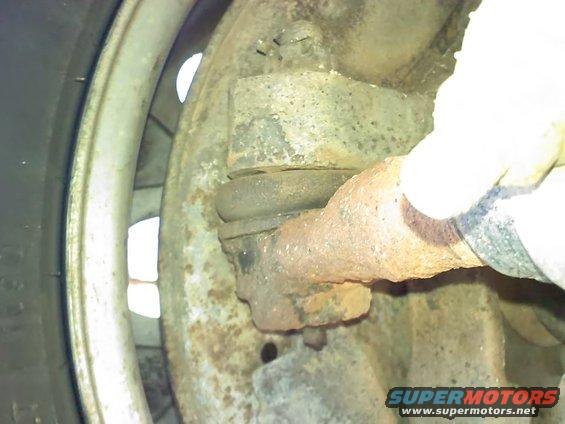 Close-up of rusty suspension ball joint with a gloved hand
