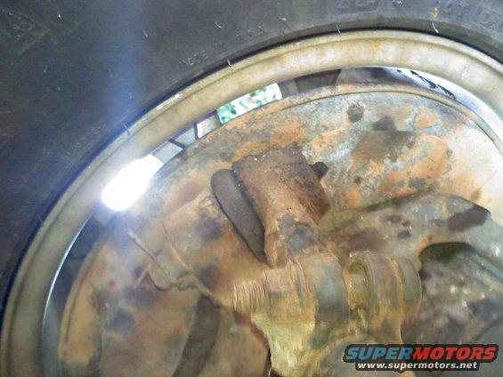 Close-up of rusty suspension parts and a tire with visible text
