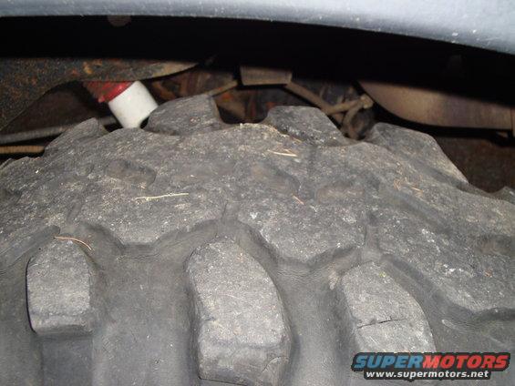 Close-up of a large, aggressive off-road tire with visible suspension components and a shock absorber