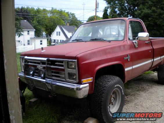 Red pickup truck with chrome grille and bumper, lifted suspension, and off-road tires