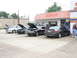 2004 Mercury Marauder - Multiple vehicles are parked in front of a building with various signs, some hoods are open.