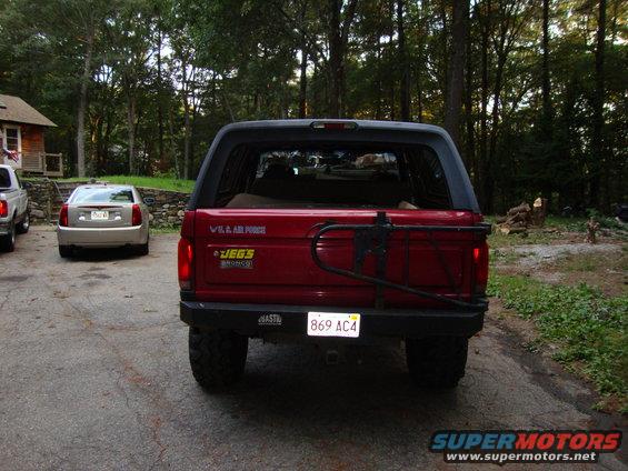Red Ford Bronco, rear view, with spare tire carrier and JEGS sticker. Another car is parked behind it