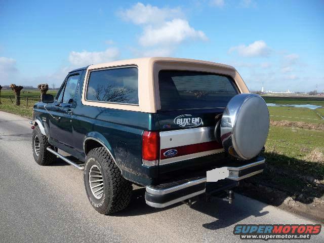 Green 1988 Ford Bronco, rear view, tan top, spare tire