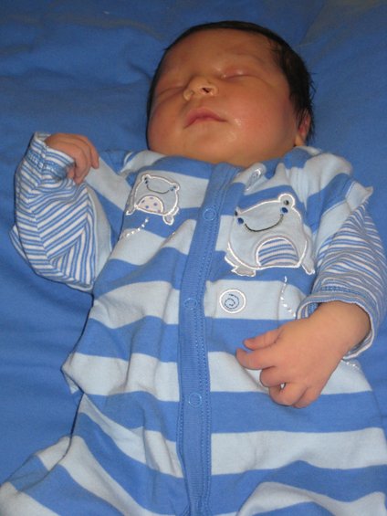Newborn baby sleeping in blue and white striped pajamas with cartoon hippos