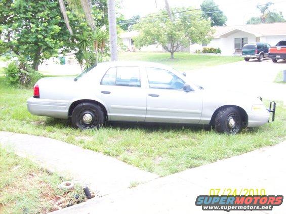 Silver 2003 Ford Crown Victoria sedan parked on grass, side view, with push bumper