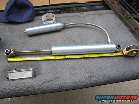 Two silver Pro Comp shocks with a yellow measuring tape and a blue cap