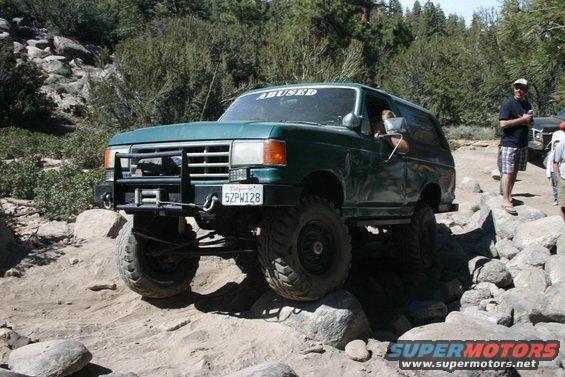 1991 Ford Bronco navigating rocky terrain, 'ABUSED' sticker on windshield