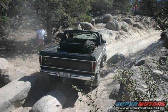 1978 Ford Bronco with spare tire in the bed, navigating a rocky off-road trail. License plate reads 6RCF780