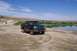 1995 Ford Bronco - A two-door Ford F-150 pickup truck is parked on a dirt path next to a calm body of water under a blue sky.