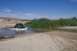 1995 Ford Bronco - A dark blue Ford F-Series truck navigates a shallow stream in a dry, sandy landscape.