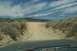 1995 Ford Bronco - View from inside a vehicle on a dusty, off-road path with desert vegetation and utility towers.
