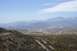 1995 Ford Bronco - A vast desert landscape unfolds with a winding road cutting through the terrain, framed by distant mountains.