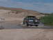 1995 Ford Bronco - A Ford Bronco navigates a water crossing in a dry, desert landscape.