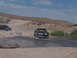 1995 Ford Bronco - A 1995 Ford Bronco navigates a shallow stream in a desert landscape, with another vehicle visible in the background.