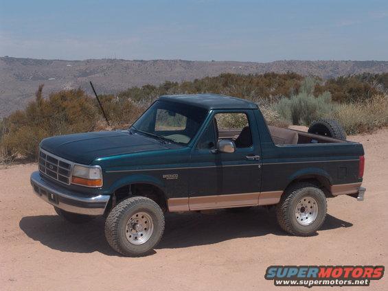 Green 1995 Ford Bronco parked on dirt road with desert hills in background