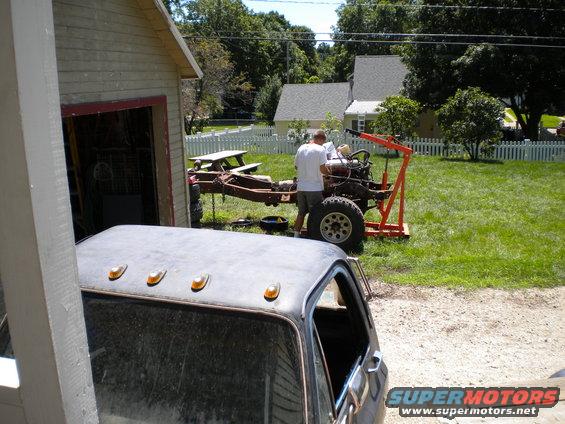 Truck chassis with engine hoist and a partial view of a dark pickup truck cab