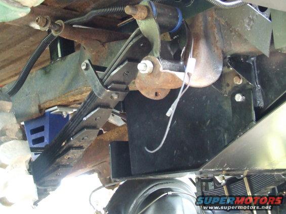 Underneath view of vehicle leaf springs, fuel tank, and suspension components. Supermotors.net logo visible