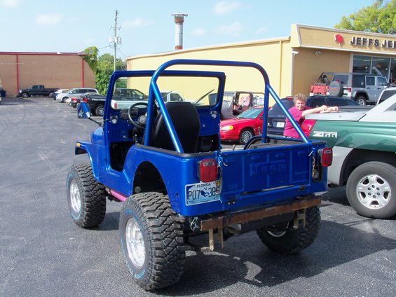 Blue Jeep CJ with roll cage, parked in lot. Florida plate P07 385