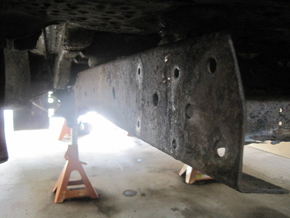 Close-up of rusty vehicle frame and suspension parts on jack stands