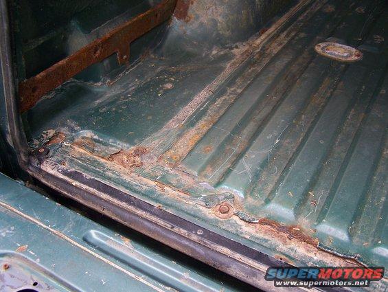 Green interior cargo area with significant rust damage along the seams and floor