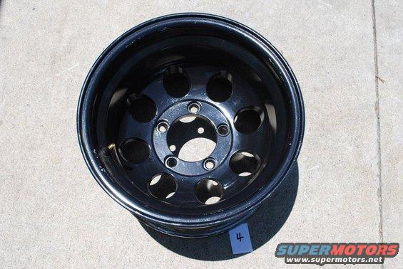 Black steel wheel with 5 lug holes and 8 circular cutouts, viewed from the front