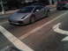 1986 Ford Bronco - A silver Lamborghini Gallardo is captured in motion on a city street, with other vehicles visible in the background.