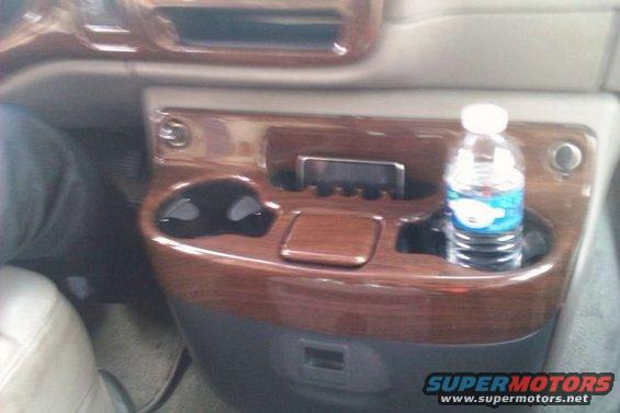 Interior console with wood trim, cup holders, and a water bottle