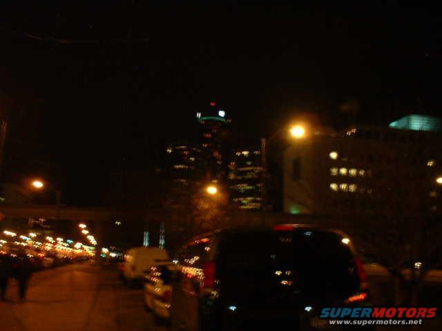 Cars on a city street at night with buildings and lights in the background