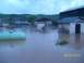 1974 Dodge 1500 - A farm scene is submerged in floodwaters, with buildings and a large propane tank visible.