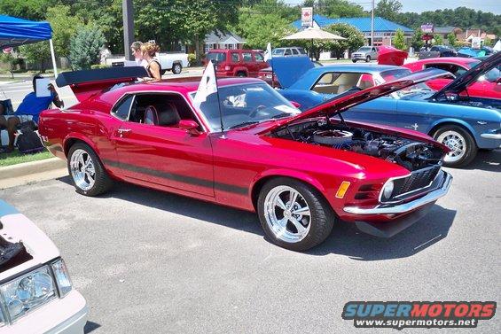 Red 1970s Ford Mustang with spoiler and racing stripes, hood open