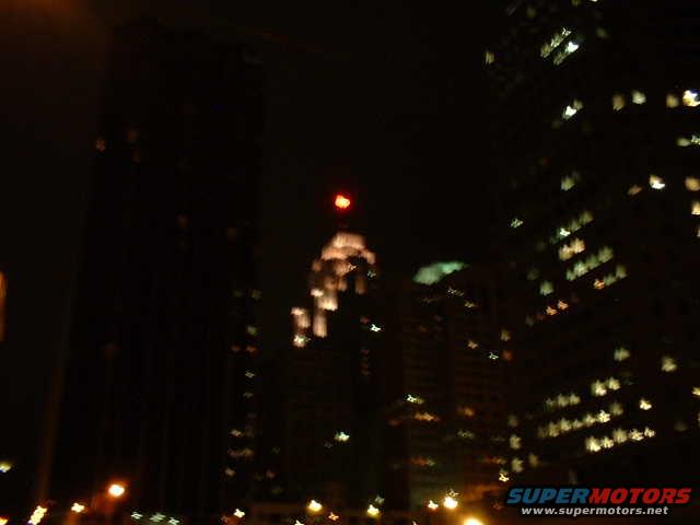 City skyline at night with blurred lights and a red beacon