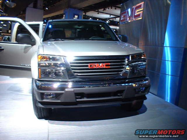 Front view of a silver GMC Canyon pickup truck with its driver's door open. The GMC logo is visible on the grille
